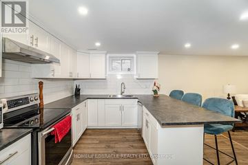 Brampton (Brampton North) apartment for rent - A kitchen with white cabinets and a black countertop.