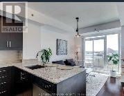 Toronto (Bayview Village) condo for rent - A modern kitchen with granite countertops and black cabinets.