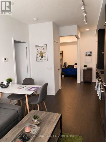 Toronto (Waterfront Communities) condo for rent - A living room with a grey couch, a wooden coffee table, and a dining table with chairs.