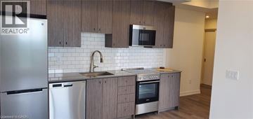 Kitchener condo for rent - A kitchen with wooden cabinets and a white tile backsplash.