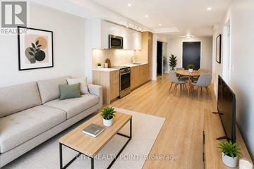 Toronto (Annex) condo for rent - A modern living room with a grey sofa, wooden coffee table, and a dining area with a grey table and chairs.