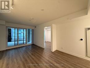 Toronto (Moss Park) condo for rent - A spacious room with wood flooring and a large window.