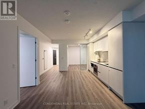 Toronto (Moss Park) condo for rent - A spacious kitchen with white cabinets and a wooden floor.