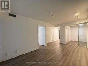Toronto (Moss Park) condo for rent - A room with wood flooring and white walls, with a door on the left and a glass door on the right.