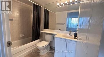 Toronto (Willowdale East) condo for rent - A white bathroom with a toilet, sink, and mirror.