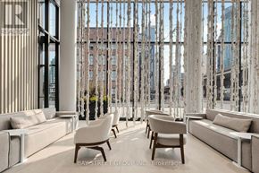 Toronto (Waterfront Communities) condo for rent - A modern living room with white furniture and a large window with a view of the city.