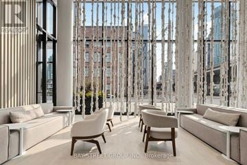 Toronto (Waterfront Communities) condo for rent - A modern living room with white furniture and a large window with a view of the city.