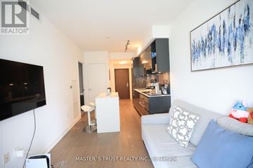 Toronto (Annex) condo for rent - A living room with a white couch and a television on the wall.