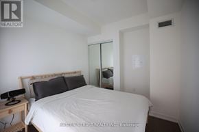 Toronto (Annex) condo for rent - A bedroom with a bed, nightstand, and mirror.