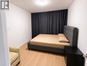 Vancouver apartment for rent - A bedroom with a bed, chair, and black curtains.