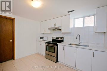 Toronto (Don Valley Village) apartment for rent - A kitchen with white cabinets and a black stove top oven.