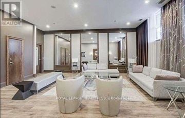 Toronto (University) condo for rent - A spacious living room with a glass table and white sofas.