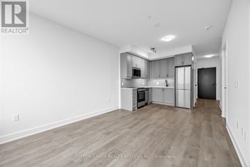 Oakville (Wm Westmount) condo for rent - A spacious kitchen with white cabinets and a wooden floor.