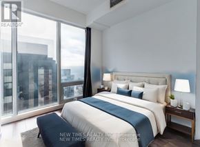 Toronto (Waterfront Communities) condo for rent - A bedroom with a large bed and a view of the city.