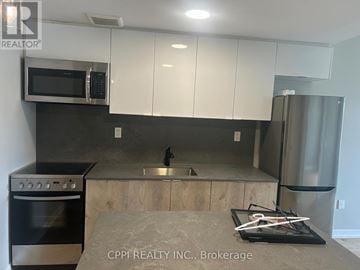 Oshawa (Central) condo for rent - A kitchen with white cabinets and a black stove top oven.