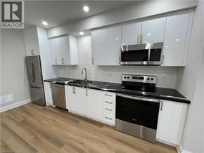 Kitchener apartment for rent - A kitchen with white cabinets and black countertops.