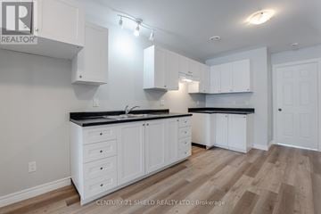North Stormont apartment for rent - A kitchen with white cabinets and a black countertop.