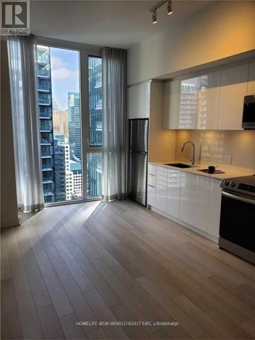 Toronto (Waterfront Communities) condo for rent - A modern kitchen with a refrigerator, sink, and a view of the city.
