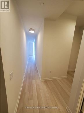 Toronto (Waterfront Communities) condo for rent - A long hallway with wood floors and white walls.