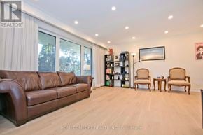 Toronto (Don Valley Village) apartment for rent - A brown leather couch sits in a well-lit room with a bookshelf and two chairs.