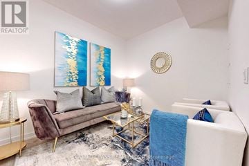 Toronto (Newtonbrook East) townhouse for rent - A living room with a white couch, a brown chair, and a coffee table with a blue blanket on it.
