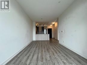 Toronto (Regent Park) condo for rent - A spacious room with wooden flooring and white walls, with a doorway leading to another room.