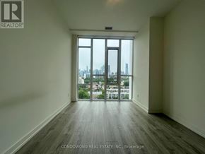 Toronto (Regent Park) condo for rent - A large empty room with a view of the city through the windows.