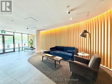 Toronto (Yorkdale-Glen Park) condo for rent - A modern living room with a blue couch and a lamp.