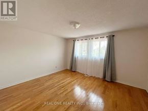 Mississauga (Meadowvale) apartment for rent - A room with wooden flooring and white walls, with a window covered by grey curtains.