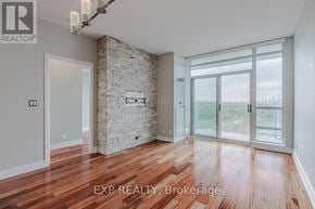 Toronto (South Parkdale) condo for rent - A room with wooden floors and a stone wall with a glass door leading outside.