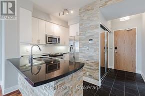 Toronto (South Parkdale) condo for rent - A kitchen with a stone column and a black counter top.