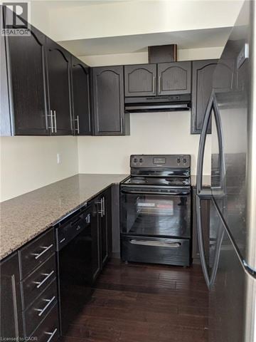 Kitchener townhouse for rent - A kitchen with black cabinets and a stainless steel refrigerator.
