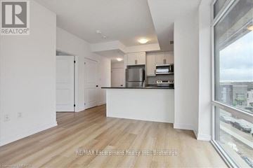 Hamilton (Waterdown) condo for rent - A spacious kitchen with white cabinets and a large window overlooking the city.