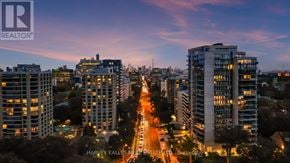 Toronto (Forest Hill South) condo for rent - A cityscape at dusk with tall buildings and a street in the foreground.