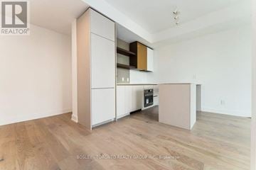 Toronto (Greenwood-Coxwell) condo for rent - A kitchen with a white cabinet and wooden floors.