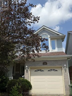 Guelph (Kortright West) apartment for rent - A house with a white garage door and a tree in front.