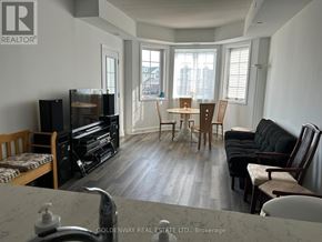 Clarington (Newcastle) condo for rent - A living room with a black couch and a wooden dining table.