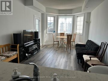 Clarington (Newcastle) condo for rent - A living room with a black couch and a wooden dining table.
