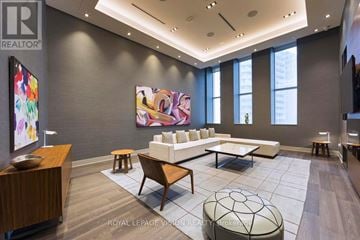 Toronto (Waterfront Communities) condo for rent - A modern living room with a large painting on the wall and a white sofa.