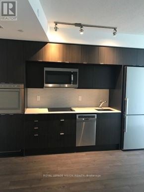 Toronto (Waterfront Communities) condo for rent - A modern kitchen with black cabinets and stainless steel appliances.