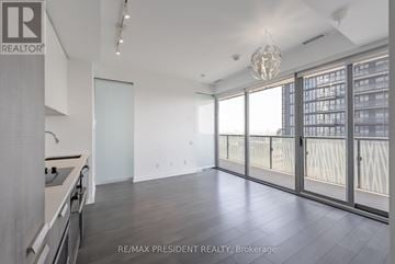 Toronto (Church-Yonge Corridor) condo for rent - A spacious room with a kitchen area and a view of a cityscape through the windows.