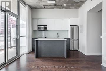 Toronto (Waterfront Communities) condo for rent - A modern kitchen with white cabinets and a dark island.