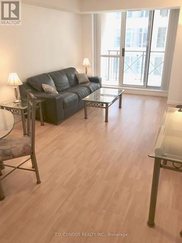 Toronto (Waterfront Communities) condo for rent - A living room with a black couch and a glass table.