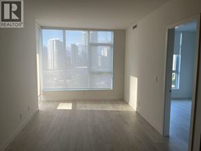 Coquitlam apartment for rent - A large empty room with a view of the city through the windows.