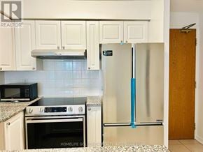 Toronto (Willowdale West) condo for rent - A kitchen with white cabinets and a black microwave above the stove.