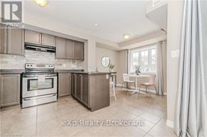 Guelph (Victoria North) townhouse for rent - A modern kitchen with a stainless steel oven and a dining area with a table and chairs.