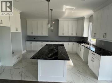 Amherstburg apartment for rent - A kitchen with white cabinets and a black island.