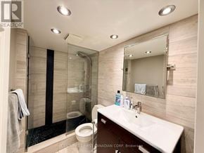London East (East E) condo for rent - A bathroom with a toilet, sink, mirror, and shower.