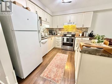 Kitchener apartment for rent - A kitchen with a white refrigerator and a patterned rug on the floor.