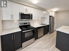 St. Catharines (Downtown) multi-family for rent - A kitchen with black cabinets and stainless steel appliances.